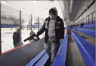  ?? Pete Paguaga / Hearst Connecticu­t Media ?? Benjamin Moreno, of Bennett Rink in West Haven, disinfects the stands where teams get changed.