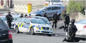  ?? PHOTO: SUPPLIED ?? Detained . . . A man sits on the ground while armed offenders squad officers swarm around a Wansbeck St address in Oamaru yesterday.