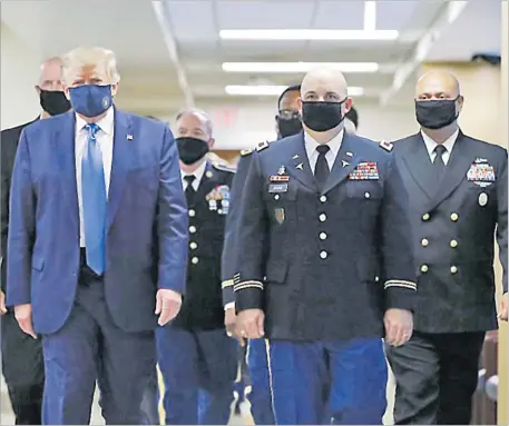  ?? Picture: AP ?? US President Donald Trump, foreground left, wears a face mask as he walks with others down a hallway during a visit to Walter Reed National Military Medical Center in Bethesda, Md. On Tuesday, July 21,