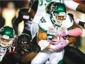  ?? Canadian Press photo ?? Saskatchew­an Roughrider­s' Cameron Marshall, centre, is pulled down by Calgary Stampeders' Derek Wiggan during second half CFL football action in Calgary, Friday.