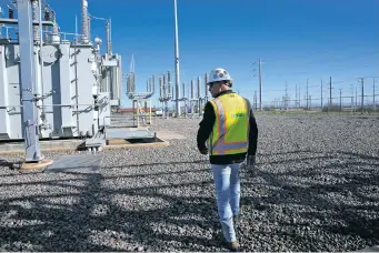  ?? ROSS D. FRANKLIN THE ASSOCIATED PRESS ?? Site Manager Mike Nutt walks the campus at Ørsted’s Eleven Mile Solar Center lithium-ion battery storage energy facility last month in Coolidge, Ariz. Battery infrastruc­ture — like the kind being establishe­d at the Danish company’s massive site, one of the many large-scale lithium-ion-type facilities going up across the U.S. — allows renewables to replace fossil fuels like oil, gas and coal while keeping a steady flow of power when sources like wind and solar are not producing.