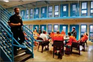  ?? AP PHOTO BY JULIE JACOBSON ?? A guard makes his rounds checking cells as inmates gather for a session with Soldier On, Chaplain Quentin Chin inside the veteran’s pod at the Albany County Correction­al Facility, Monday in Albany, N.Y.