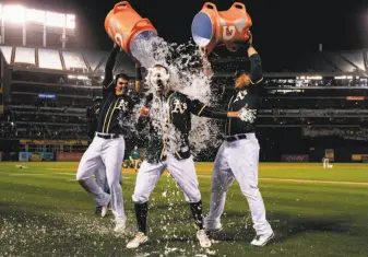  ?? Jason O. Watson / Getty Images ?? Ryon Healy (left) and Bruce Maxwell give Adam Rosales the bucket treatment after Rosales hit a two-out, two-run walk-off single to give the A’s a victory over the Tigers.