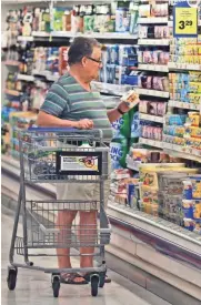  ?? ASSOCIATED PRESS ?? A shopper looks at an item in the dairy section of a Kroger grocery store in Richardson, Texas.