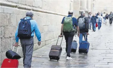  ?? Lavandeira Jr / Efe ?? Unos turistas con sus maletas en Santiago de Compostela.