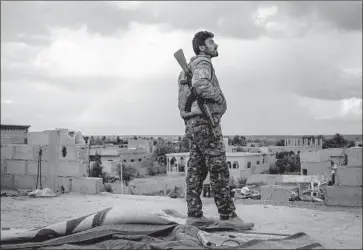  ?? Chris McGrath Getty Images ?? A FIGHTER with the Syrian Democratic Forces keeps watch from a rooftop on the outskirts of town on Sunday in Baghouz al Fawqani, Syria. Islamic State militants are said to be using some civilians as human shields.