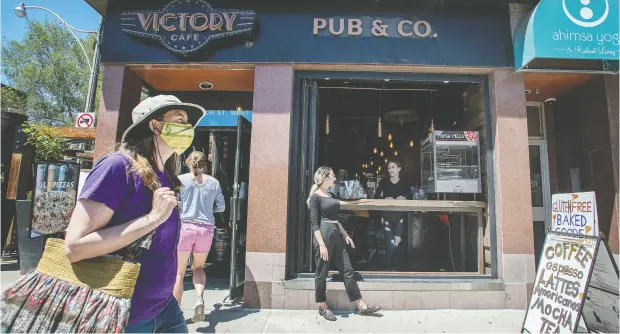  ?? PETER J. THOMPSON / NATIONAL POST ?? People pass by Toronto’s Victory Cafe Pub Monday. The Greater Toronto Area and Hamilton will reopen patio dining later than other parts of Ontario.