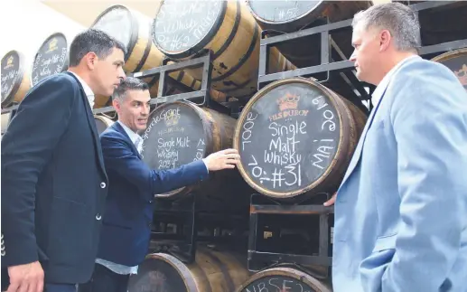  ?? Acadie Nouvelle: Réal Fradette ?? Le président et cofondateu­r de la Distilleri­e Fils du Roy de Petit-Paquetvill­e, Sébastien Roy, explique aux députés Serge Cormier et Robert Gauvin le processus de vieillisse­ment du whisky. -