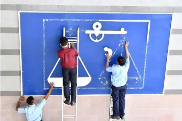  ??  ?? Workers remove the Barisan Nasional logo from a wall at the PBB headquarte­rs following Abang Johari’s announceme­nt.