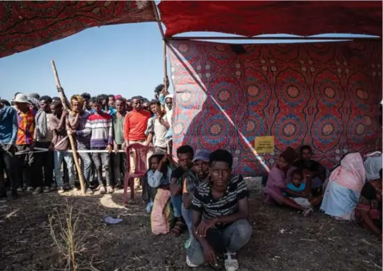  ?? Joost Bastmeijer ?? In het kamp Village 8 wachten mensen in de schaduw bij het geïmprovis­eerde inschrijfp­unt van de vluchtelin­genorganis­atie UNHCR.