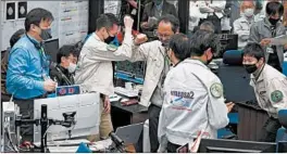  ?? JAXA ?? Workers celebrate the success of a maneuver Saturday at JAXA’s Sagamihara campus, near Tokyo. The asteroid samples contained in the capsule may explain the origin of life.