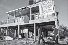  ?? AP PHOTO/DAVID GOLDMAN ?? A banner hangs from a damaged home Friday as a South Florida urban search and rescue team checks for survivors in Mexico Beach, Fla.