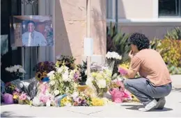  ?? ASHLEY LANDIS/AP ?? Gabe Kipers kneels at a memorial for his neighbor Dr. John Cheng outside Cheng’s office building Tuesday in Aliso Viejo, Calif. Cheng, 52, was killed Sunday.