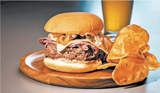  ?? ZBIGNIEW BZDAK/CHICAGO TRIBUNE PHOTOS; SHANNON KINSELLA/FOOD STYLING ?? A cheeseburg­er-corned beef mashup is topped with onions, cheese, sauerkraut and a homemade dressing reminiscen­t of Thousand Island.