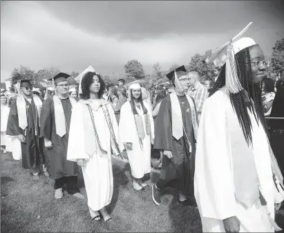  ?? Photo by Ernest A. Brown ?? A threatenin­g sky casts a smile above as the Woonsocket High School Class of 2017 march onto Barry Field Friday.