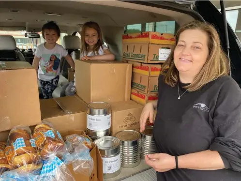  ?? Haley Overbeek/Northern Illinois Food Bank via AP ?? ■ In this image provided by the Northern Illinois Food Bank, Kisha Galvan and her grandchild­ren pose for a photo after stocking up on food items from the Northern Illinois Food Bank on May 26 in Rockford, Ill. Galvan was able to stock up on groceries for the week and buy extras like clothing and shoes at Walmart for her children last year.