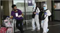  ?? (AFP) ?? Passengers wearing personal protective suits walk to the check-in area at the internatio­nal airport in Manila.