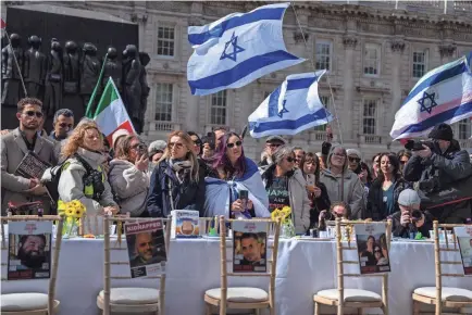  ?? CARL COURT/GETTY IMAGES ?? At a demonstrat­ion in London on Wednesday, people gather around an empty Passover Seder table featuring empty chairs for the hostages taken by Hamas on Oct. 7.