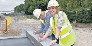  ?? Richard-Holton ?? ●●Councillor­s Becky Crawford and Chris Murphy sign their names on one of the beams at the new Brinningto­n leisure centre