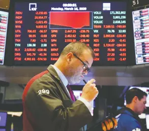  ?? LUCAS JACKSON / REUTERS ?? Traders work on the floor of the New York Stock Exchange shortly after
the opening bell Monday as trading is halted.