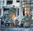  ??  ?? Fighters find some warmth in what remains of the bombed out city of Aleppo