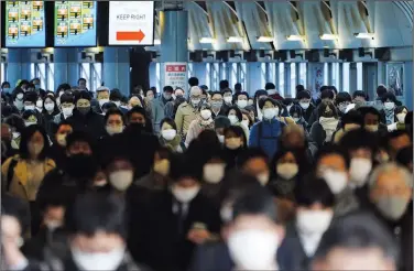  ?? (File Photo/AP/Eugene Hoshiko) ?? A station passageway is crowded with commuters wearing masks Jan. 8, 2021, during a rush hour in Tokyo. Stories circulatin­g online incorrectl­y claim 100 million humans in the same place would emit enough radiation to be deadly.