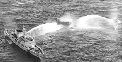  ?? Handout / Philippine Coastguard / AFP ?? In this frame grab from aerial video footage taken on March 5, 2024 and released by the Philippine Coast Guard (PCG), Chinese Coast Guard ships (L and R) deploy water cannons at the Philippine military-chartered civilian boat Unaizah May 4 (C) during its supply mission near Second Thomas Shoal in the disputed South China Sea.