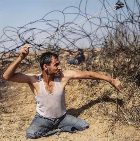  ??  ?? Taking aim: Double amputee Saber al-Ashkar, 29, swings a rock around his head at the border protest