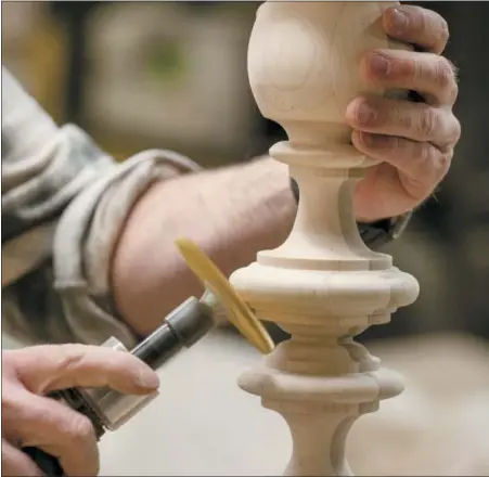  ?? ETHAN ALLEN VIA AP ?? In this photo provided by Ethan Allen, a craftsman is shown sanding the detailed shapes of the Ethan Allen Quincy Bed post with a hand-held brush sander in their North American workshops..