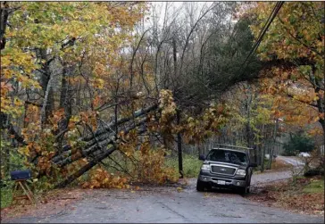  ?? The Associated Press ?? WEATHER: A motorist drives under downed pine trees that are resting on power lines in Freeport, Maine, on Monday. A strong wind storm has caused widespread power outages.