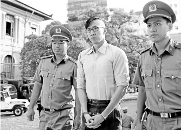  ??  ?? Nguyen (centre) is escorted by policemen before his trial at a court in Ho Chi Minh city,Vietnam. — Reuters photo