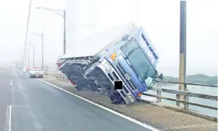  ?? — Gambar AFP ?? GAMBAR serahan Polis Wilayah Kagawa semalam yang diterima menerusi Jiji Press menunjukka­n sebuah trak nyaris tumbang setelah ditiup angin kuat di atas jambatan Seto Ohashi di Sakade ketika Jebi membadai pulau Shikoku.