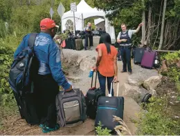  ?? CHARLES KRUPA/AP 2017 ?? A Royal Canadian Mounted Police officer informs a migrant couple of the location of a legal border station, shortly before they crossed over to Quebec illegally.