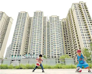  ?? AFP FILE PHOTO ?? Boys play basketball beside a housing complex constructe­d by Evergrande in China’s capital Beijing on July 28, 2022.