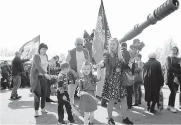  ?? ALEXEI ALEXANDROV/AP ?? Ukraine remembers: A girl wearing Soviet-era military uniform and her relatives walk during Victory Day celebratio­ns Saturday at a World War II memorial in Saur-Mogila, Ukraine, near the Russian border. Efforts have stalled to end the conflict between Russia-backed rebels and Ukrainian forces that’s killed more than 14,000 people since 2014.