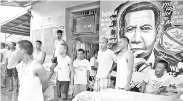  ??  ?? File photo shows inmates standing next to a portrait of Duterte inside the city jail in Manila. — AFP photo