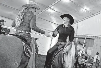  ?? SOURCE: CONGRESS MATERIALS ?? Jessica Batton, right, is congratula­ted by Emily Opell after Batton finished first in youth reining in the 14-18 age group.