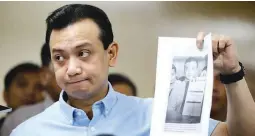  ?? (Czar Dancel) ?? HERE'S MY PROOF – Sen. Antonio Trillanes IV holds up a photo of him and his amnesty applicatio­n during a press conference at the Senate building Thursday.