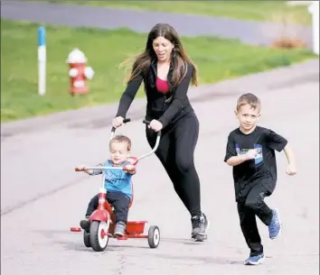  ?? Pam Panchak/Post-Gazette ?? Melissa Orehowsky pushes her 2-year-son, Austin, while her oldest son, Brendan, 5, runs in Sewickley on Tuesday while training for the Pittsburgh Marathon. Austin is training for the Toddler Trot and Brendan for the one-mile run.