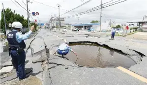  ?? — Gambar Jiji Press/AFP ?? POLIS memeriksa lubang besar di atas jalan raya selepas gempa bumi melanda Takatsuki, di utara wilayah Osaka di Jepun semalam.