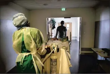  ?? Francois Mori Associated Press ?? AMIENS-PICARDIE HOSPITAL workers move a COVID patient for tests earlier this week. As a new surge of the disease overwhelms many French hospitals, critics say officials are putting politics over public health.