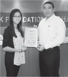  ??  ?? Kuok Foundation general manager Ng Teck Seng (right) presents the scholarshi­p to a student.