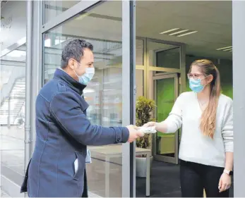  ?? FOTO: ANKE KUMBIER ?? Samet Akinci (links) holt sich bei Viktoria Peschkov vom Bürgerbüro sechs Masken ab. Der Gastronom ist wegen Corona finanziell stark gebeutelt. Die Masken gibt es, solange der Vorrat reicht.