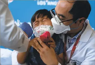 ?? Jae C. Hong Associated Press ?? CALLUM DIAZ-CHENG, 3, in the arms of his father, Dr. Andrew Cheng, gets a dose of Pfizer-BioNTech’s COVID-19 vaccine Tuesday at Children’s Hospital Los Angeles. The shot is 10% the amount of the adult dose.