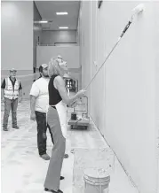  ?? Elizabeth Conley / Houston Chronicle ?? Secretary of Education Betsy DeVos helps paint a wall at Kingwood High School on Wednesday. Repairs to the school are estimated at $70 million.