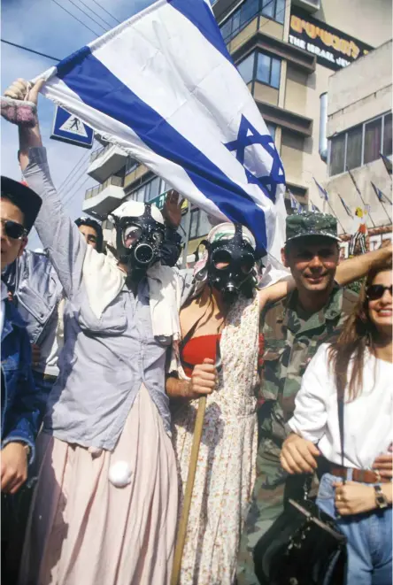  ?? (Alex Levac, IDF Archive) ?? AN AMERICAN soldier joins a Purim celebratio­n in the streets of Israel as the Gulf War ends. All photos: Feb. 1991 unless otherwise indicated.