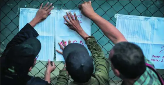  ?? / MIGUEL GUTIÉRREZ (EFE) ?? Tres ciudadanos buscan su mesa electoral para votar en los comicios municipale­s el domingo en Caracas.