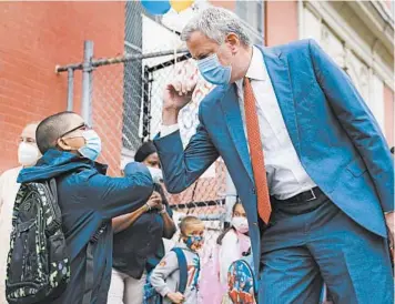  ?? JOHN MINCHILLO/AP ?? Big back-to-school test: New York Mayor Bill de Blasio greets students as they arrive for in-person classes Tuesday at Public School 188 in Manhattan. Hundreds of thousands of elementary school students headed back to classrooms as New York City enters a high-stakes phase of resuming in-person learning during the coronaviru­s pandemic.