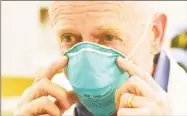  ?? Tyler Sizemore / Hearst Connecticu­t Media ?? Dr. Michael Parry, chief of infectious diseases at Stamford Hospital, demonstrat­es an N-95 medical mask.