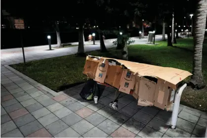  ?? Photograph: Rebecca Blackwell/AP ?? A person sleeps inside a makeshift shelter on park bench in downtown Miami on 25 January 2024.